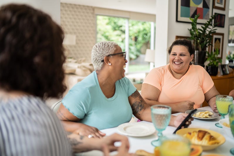 Three women sitting around a table laughing