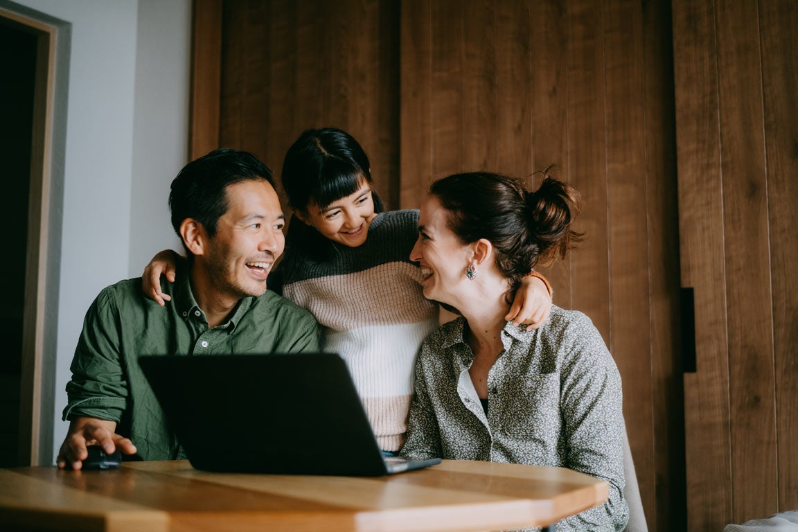 Parents sitting in front of laptop with daughter between them