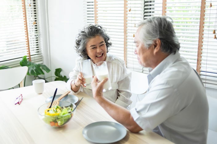 Asian Senior Adult couple holding glasses of milk together 