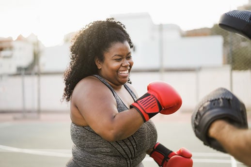 Woman practicing boxing with trainer outside the shot