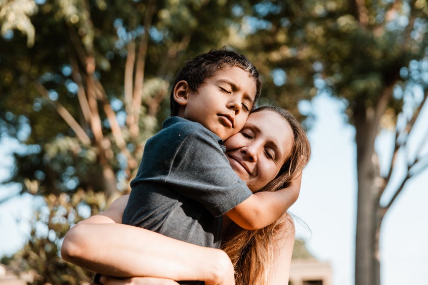 Young boy hugging his mom in park