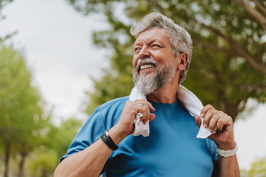 older man smiling while looking off to the side, towel around his neck