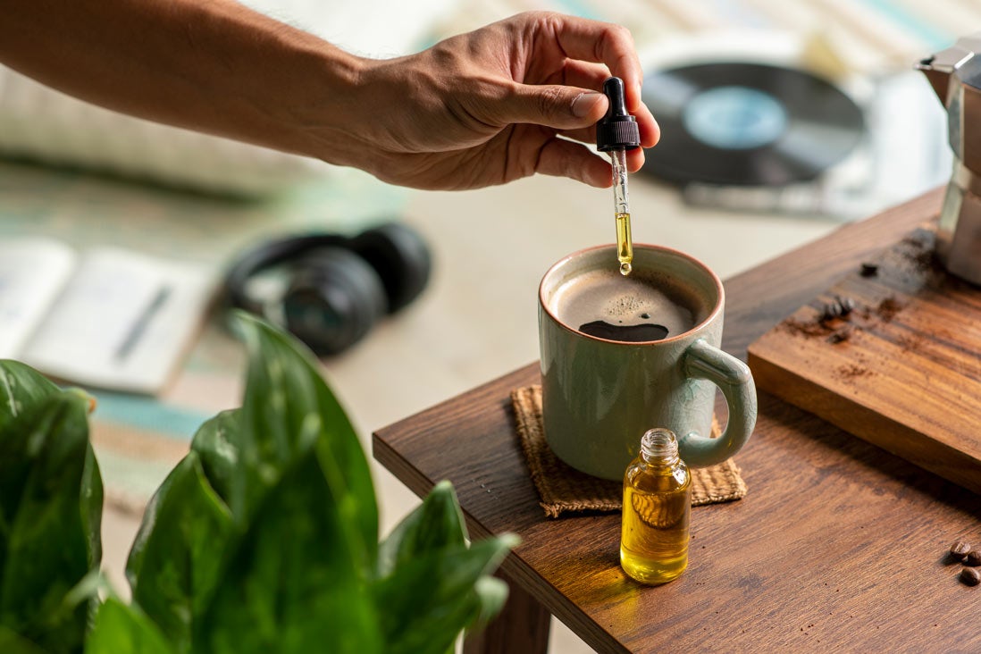 Person putting remedy into a mug with oil dropper