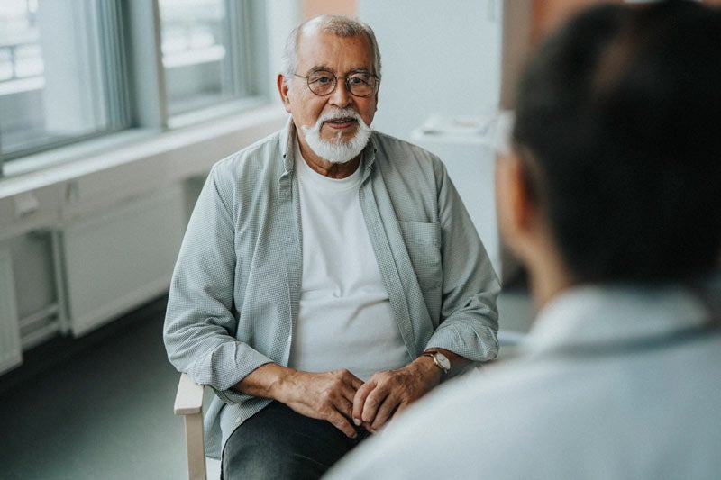 Older man speaking with doctor at medical clinic