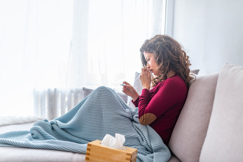 Woman checking her temperature while not feeling well