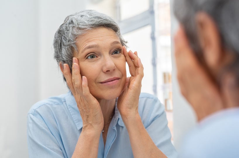 Mature woman looking at skin in mirror